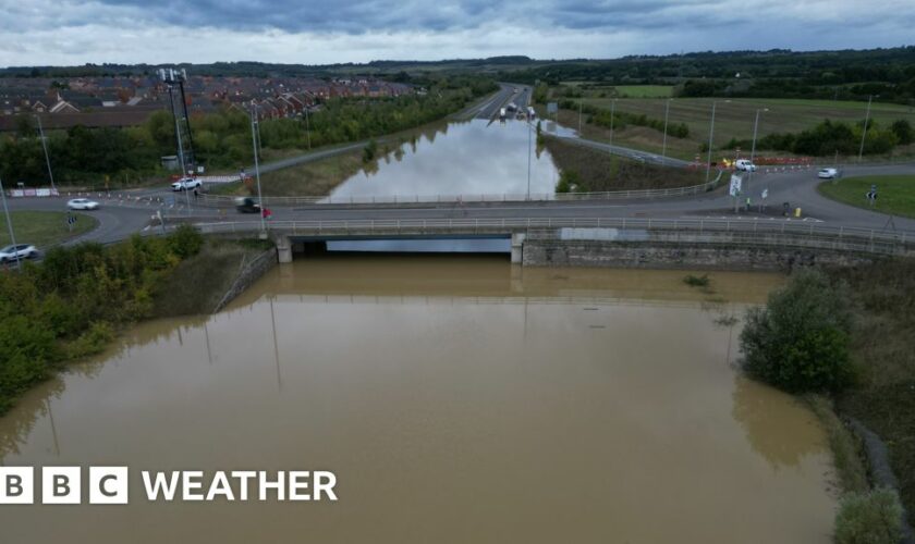 A dual carriageway completely covered by flood water under a bridge