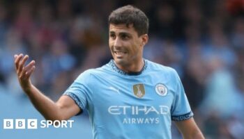 Rodri holds his hands to his face during a press conference