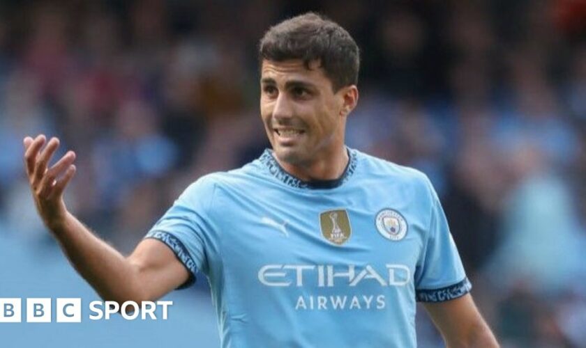 Rodri holds his hands to his face during a press conference