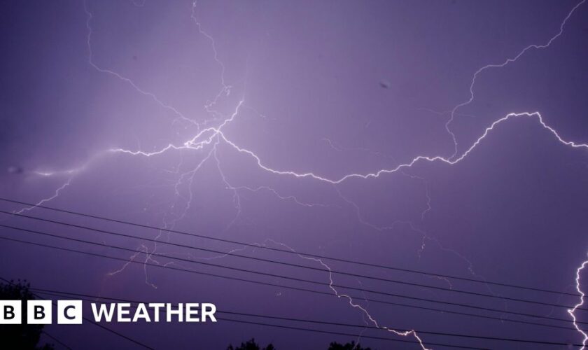 Night sky turning a purple hue as fork lighting spreads across the sky.