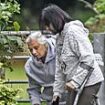 Wife of grandfather, 80, 'kicked to death yards from his front door' visits floral tributes laid next to park where he was killed - as police continue to quiz boy, 14, over 'murder'