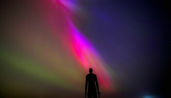 The aurora borealis, also known as the northern lights, glow on the horizon at Another Place by Anthony Gormley, Crosby Beach, Liverpool , Merseyside . Picture date: Friday May 10, 2024. PA Photo. See PA story WEATHER Aurora. Photo credit should read: Peter Byrne/PA Wire