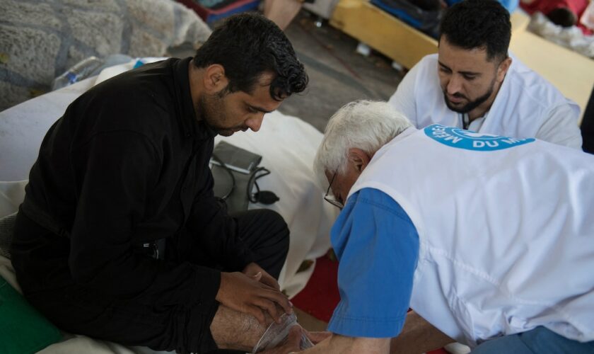 Le docteur Bertrand Chatelain de l'ONG Médecins du Monde (MdM) examine un réfugié lors d'une maraude dans le camp de migrants du quartier Stalingrad à Paris, le 12 juillet 2023. (Photo par JULIEN DE ROSA / AFP)