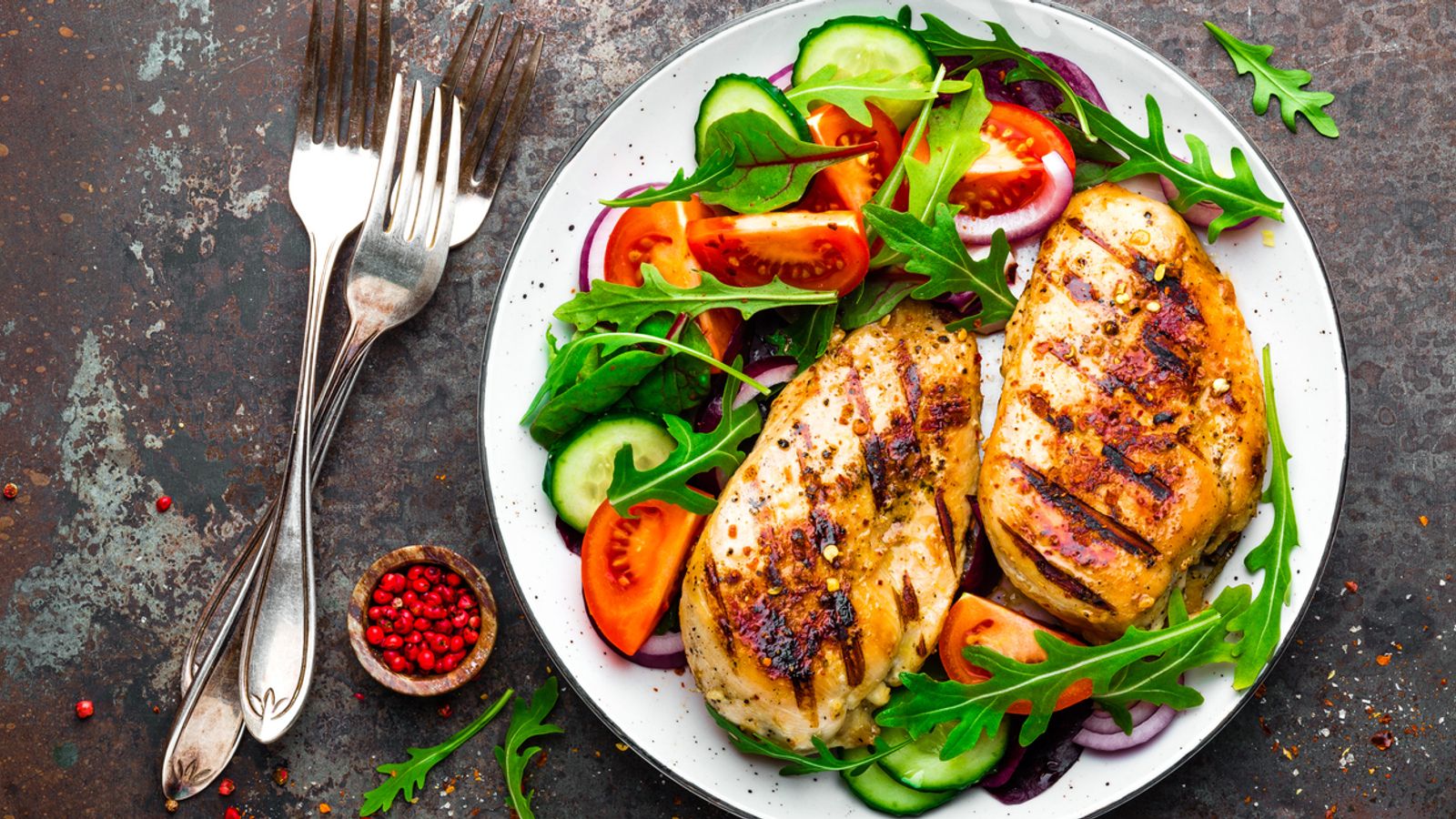 Grilled chicken breast. Fried chicken fillet and fresh vegetable salad of tomatoes, cucumbers and arugula leaves. Chicken meat with salad. Healthy food. Flat lay. Top view. Dark background