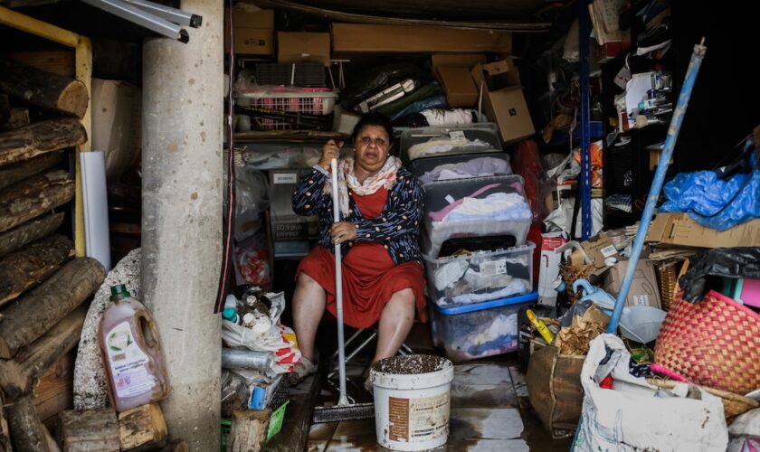 Une femme essuie la boue du sol d'une maison le 18 octobre 2025 dans le village de Limony, dans le sud de la France, un jour après que le village ait été coincé dans des inondations suite à de fortes pluies dans le département de l'Ardèche.