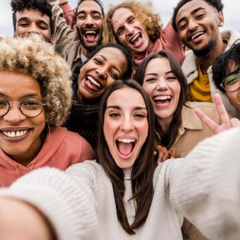 Eine Frau lacht mit vielen Freundin auf einem Selfie.